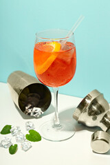 Concept of summer cocktail, Aperol Spritz on white table against blue background