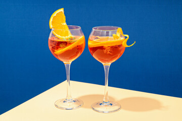 Concept of summer cocktail, Aperol Spritz on beige table against blue background