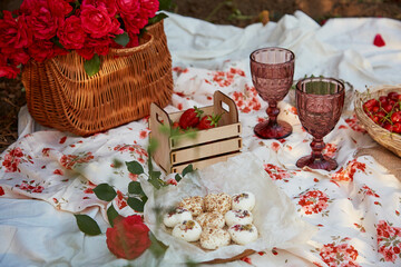 Feminine pink summer picnic with tablecloth, marshmallows, strawberries, cherry, peas and glasses...