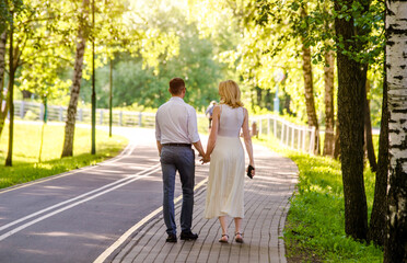 Fototapeta premium A guy and a girl walk along the path in the city Park 