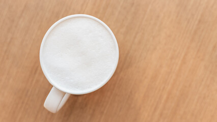 Hot fresh milk in white ceramic mug on wooden table top view with copy space, Flat lay milk cup on wooden, Morning milk.