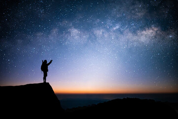 Silhouette of young man standing and watched the star, milky way and night sky alone on top of the...