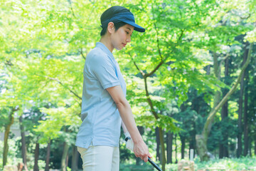 スイングするゴルフウェアを着た日本人女性