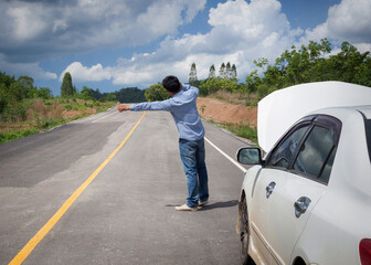 Man hitchhiking by a broken car