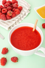 Raspberry drink with fresh juice in white mug. Antioxidant breakfast. Red cold beverage and berries on table. Natural vegetarian liquid dessert.