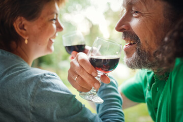 middle-aged couple drinking red wine from glasses outside , hipster man with long hair and beard