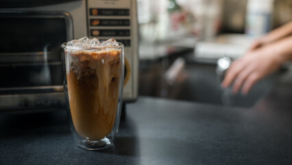 Ice coffee on a table with cream being poured into it showing the texture