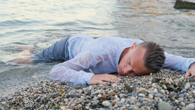 Tired dressed man lies on the seashore