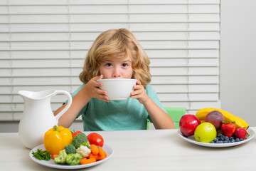 Hunger, appetite concept. Kid boy eating healthy food vegetables. Breakfast with milk, fruits and...