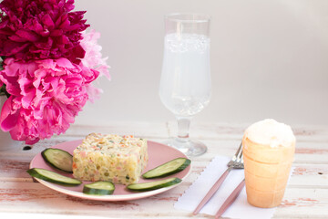 Olivier salad on a plate. Bouquet of fragrant peonies, serving dishes in the restaurant