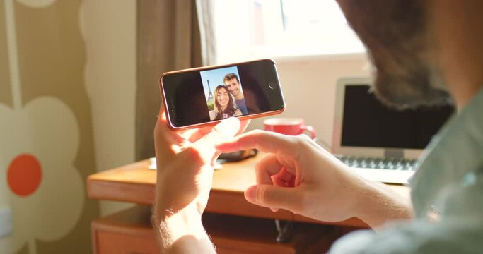 A man looking through photos of himself and his partner on his mobile phone