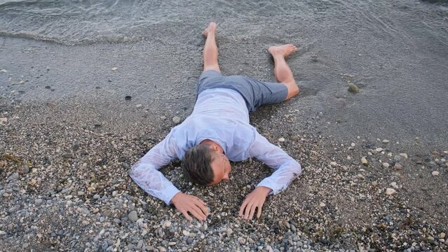 A young man in clothes lies on the seashore on a hot summer day