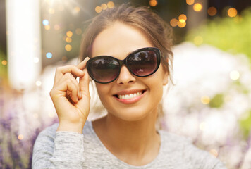 summertime, leisure and people concept - portrait of happy young woman in sunglasses at summer...