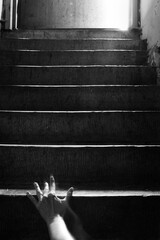 Dark image of hand crawling up the stairs.