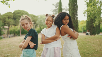 Smiling three girls friends pre-teenage cross their arms in dance move in the park