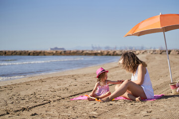 a little girl puts sunscreen on her mother's face