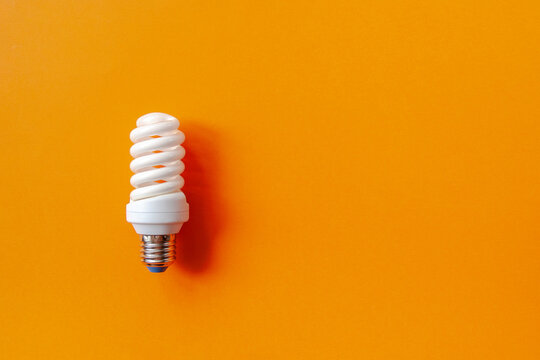 Energy saving light bulb on a orange background. Economical consumption of electricity. The concept of nature conservation