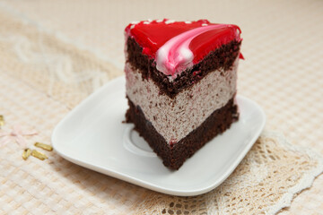 A serving of delicious sweet cake covered in red icing lies in a dessert plate