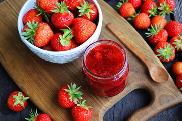 Homemade strawberry jam or marmalade in the glass jar and the fresh strawberries on the wooden rustic table