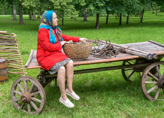A village woman goes to the fair for goods on an old wooden cart.  Reconstruction of rural lifestyle