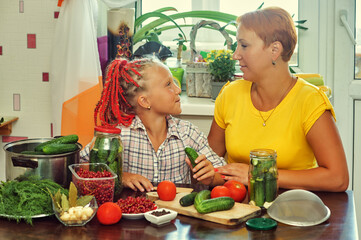 Mom and daughter are engaged in home canning vegetables.