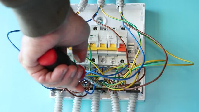 Electrical work on installation of consumer unit of fuse box with automatic switches in household electrical network.