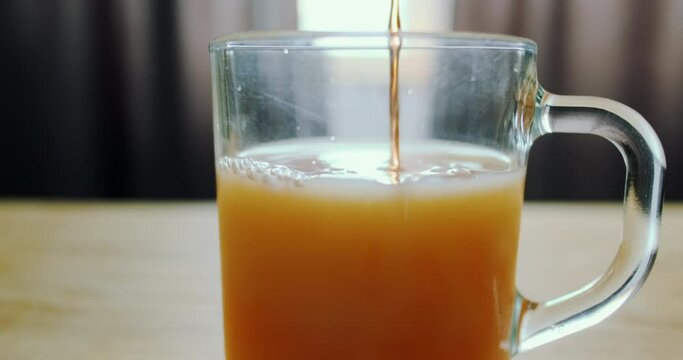 Glass cup with juice. Add liquids, fill a cup, add alcohol to juice. Close-up.