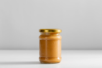 food, eating and preserve concept - close up of jar with canned vegetable puree or peanut butter on table