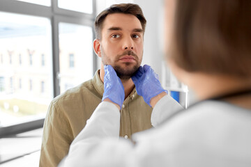 medicine, healthcare and people concept - female doctor checking lymph nodes of man patient at hospital