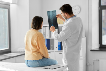 medicine, healthcare and people concept - male doctor showing x-ray to female patient at medical office in hospital - obrazy, fototapety, plakaty