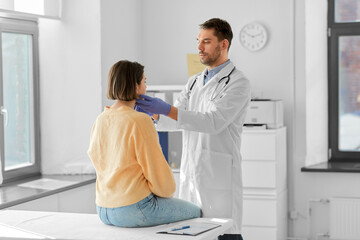 medicine, healthcare and people concept - male doctor checking lymph nodes of woman patient at...