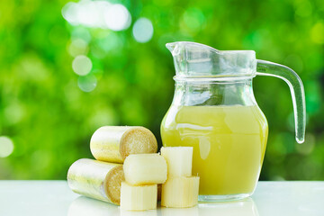 Fresh  sugar cane cut and sugar cane juice with green background. 