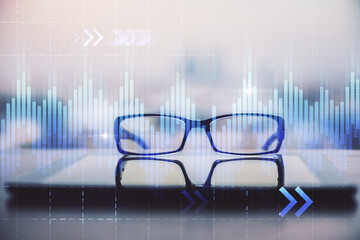 Financial graph hologram with glasses on the table background. Concept of business. Double exposure.