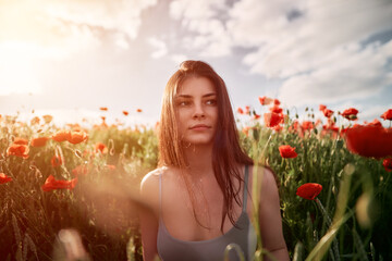Portrait of a woman in the poppy field against strong sunlight