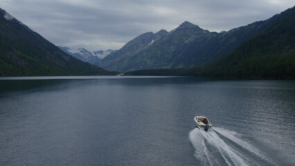 Motorboat on Multin lakes in the middle of mountains under dramatic sky in Altai