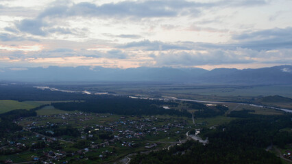 Aerial view of valley and country houses under blue sky in sunset time