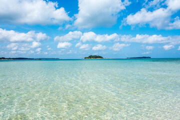 Nature seascape view of beautiful tropical beach and sea in sunny day with some clouds and islands in the horizon. Belitung, Indonesia