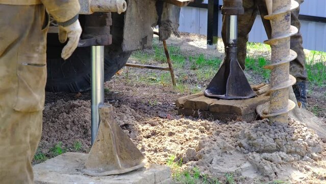 Team of workers with drilling rig on car are drilling artesian well for water in ground. Insertion of metal casing pipe into ground, installation of individual drinking supply, June 28, 2022, Russia, 