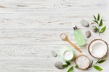 Coconut with jars of coconut oil and cosmetic cream on colored background. Top view. Free space for your text. Natural spa coconut cosmetics and organic treatment concept Coconut Spa composition