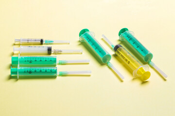 Top view of medical syringes with needles at yellow background with copy space. Injection treatment concept