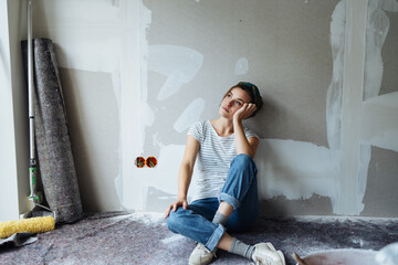Young pensive woman renovating her apartment and thinking how to paint the walls