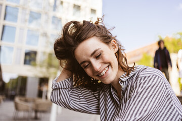 happy young woman sitting in city looking to the bottom