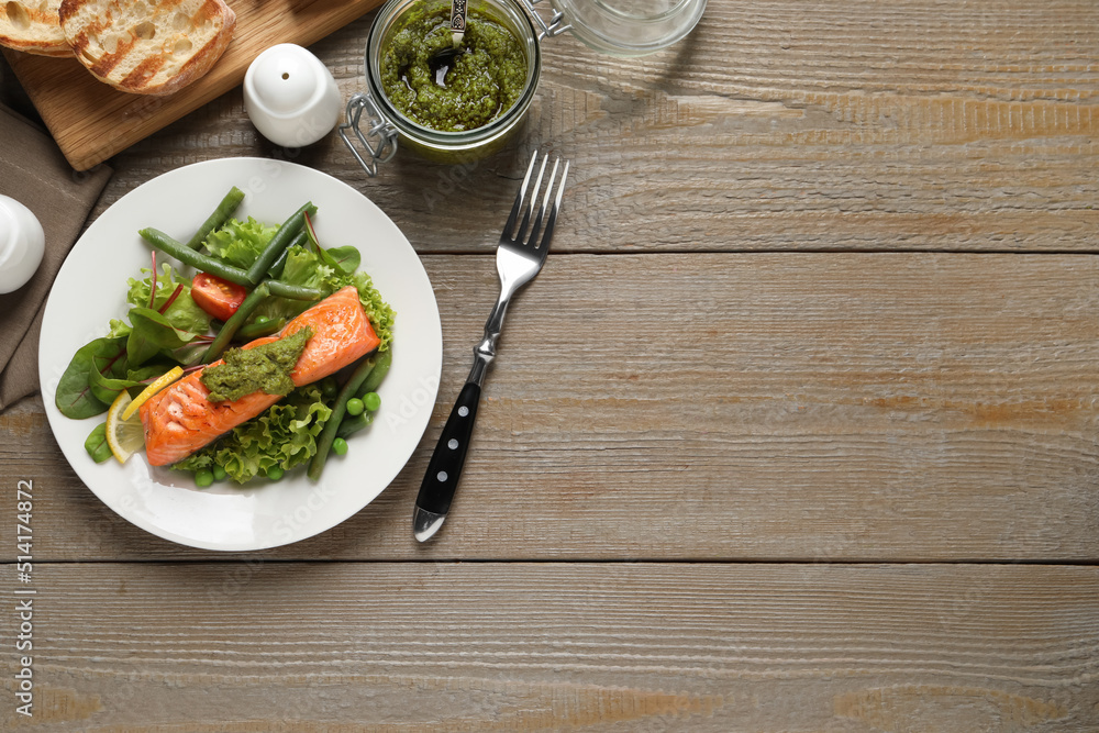 Wall mural Tasty cooked salmon with pesto sauce served on wooden table, flat lay. Space for text