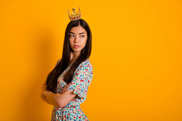 Photo of young serious selfish young egocentric female with crown on head look blank space isolated on yellow color background © deagreez