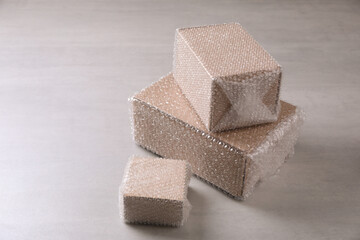 Cardboard boxes covered with bubble wrap on light grey table