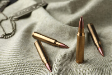 Many brass bullets on burlap, closeup. Space for text