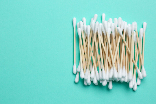 Heap of cotton buds on turquoise background, top view. Space for text