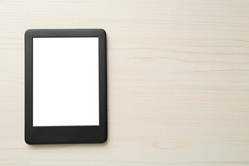 Modern e-book reader with blank screen on white wooden table, top view. Space for text