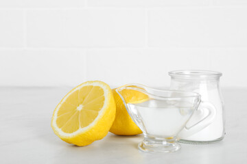 Vinegar, baking soda and lemon on white marble table. Eco friendly natural detergents