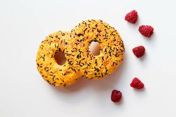 sweet dessert. round donuts with yellow icing isolated on white background and raspberries